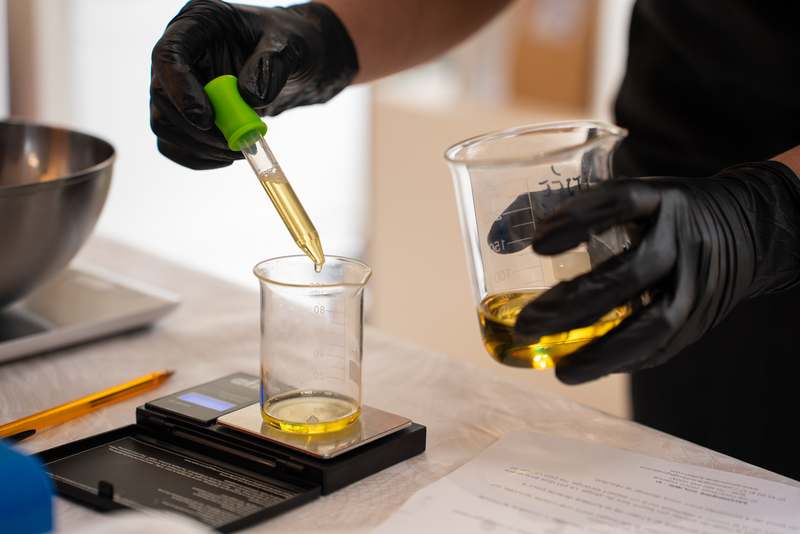 pesage des huiles essentielles sur une balance de précision, avec une pipette