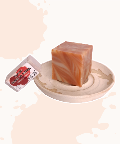 Savon marbré au format cube sur porte-savon artisanal et savon invité posé à côté